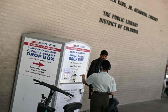 A person drops her ballot in a drop box at a polling place at the Martin Luther King Jr. Memorial Library during the DC primary elections on June 16, 2026 in Washington, DC. (Photo by Brendan SMIALOWSKI / AFP)