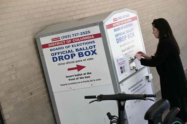 A person drops her ballot in a drop box at a polling place at the Martin Luther King Jr. Memorial Library during the DC primary elections on June 16, 2026 in Washington, DC. (Photo by Brendan SMIALOWSKI / AFP)
