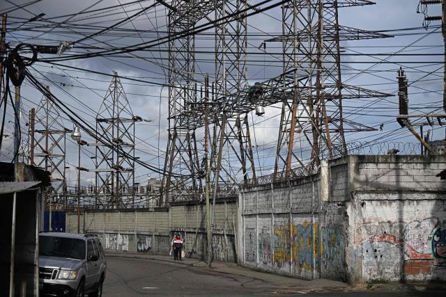 Power transmission towers and tangled electrical lines are pictured along a street in the Catia neighborhood of Caracas on June 16, 2026. Venezuela signed an agreement with US giant General Electric to begin the recovery of its beleaguered power system, acting president Delcy Rodriguez announced on June 15, 2026. (Photo by Federico PARRA / AFP)