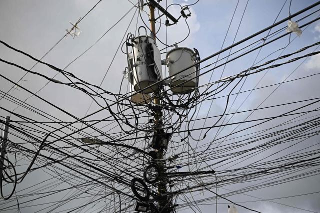 Power lines and transformers are pictured tangled around a utility pole in the Catia neighborhood of Caracas on June 16, 2026. Venezuela signed an agreement with US giant General Electric to begin the recovery of its beleaguered power system, acting president Delcy Rodriguez announced on June 15, 2026. (Photo by Federico PARRA / AFP)