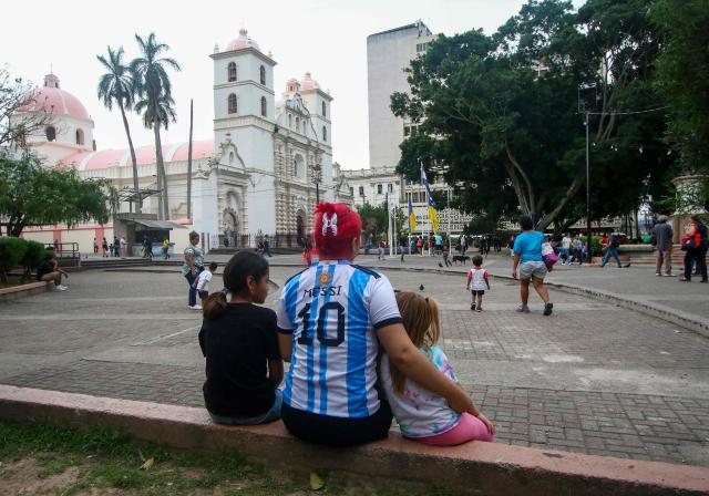 A woman wearing an Argentina national team jersey bearing the name of Lionel Messi sits with two children in a public square in Tegucigalpa on June 16, 2026. (Photo by Johny Magallanes / AFP)