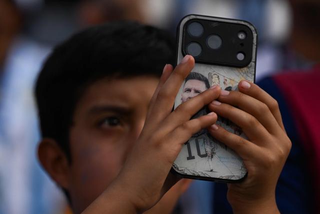 An Argentine fan takes a picture with a phone depicting Argentina's forward #10 Lionel Messi ahead of the 2026 World Cup Group J football match between Argentina and Algeria at the Kansas City Stadium in Kansas City on June 16, 2026.  (Photo by ROBERTO SCHMIDT / AFP)