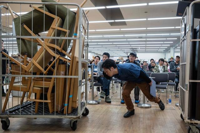 In this photo taken on May 14, 2026, a buyer looks at a cart of furniture before bidding on it at the Hamaya wholesale auction site in Higashimatsuyama, Saitama Prefecture. Under a scorching sun in a Bangkok suburb, a whistle blows and shouts fill the air as dozens of shoppers rush into a warehouse bearing the sign: "Japanese Second-Hand Store". From bags and bicycles to surfboards and suitcases, the Japanese second-hand market is booming, with quality-conscious buyers in other Asian countries increasingly tapping into the circular economy trend. (Photo by Andrew CABALLERO-REYNOLDS / AFP) / To go with "JAPAN-LIFESTYLE-ENVIRONMENT-RECYCLE,FOCUS' by Montira Rungjirajittranon with Kyoko Hasegawa