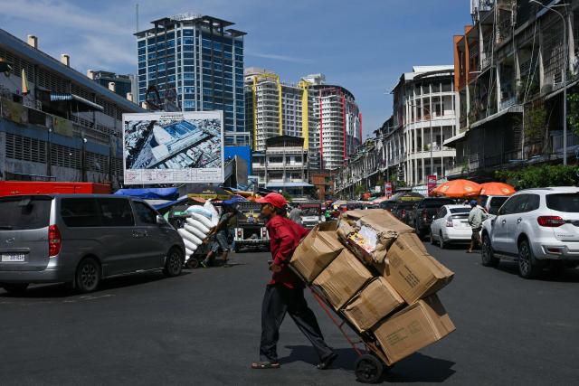 A worker pulls a cart loaded with goods outside a market in Phnom Penh on June 17, 2026. (Photo by TANG CHHIN Sothy / AFP)