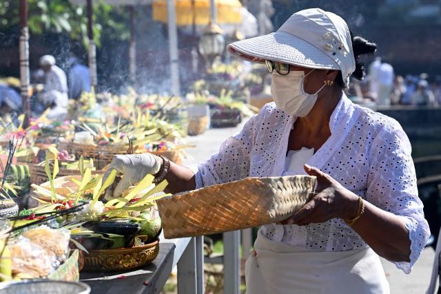 A Hindus woman places her offerings on a table to celebrate the religious festival Galungan at a temple in Denpasar on Indonesia's Bali island on June 17, 2026. Balinese Hindu adherents celebrate Galungan Day or the Earth's celebration to thank God for the creation of the Earth and its content. (Photo by SONNY TUMBELAKA / AFP)