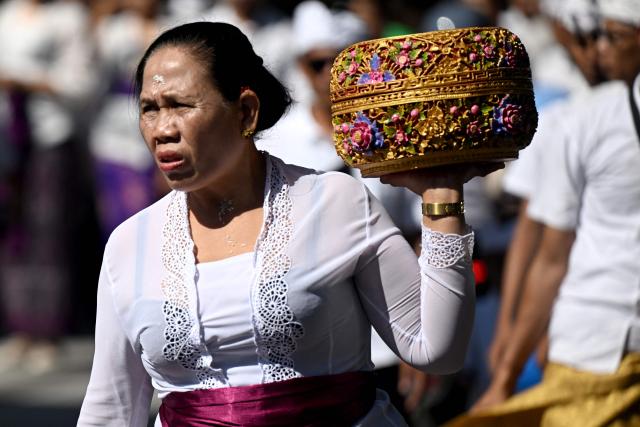 A Hindus woman carries offerings to celebrate the religious festival Galungan at a temple in Denpasar on Indonesia's Bali island on June 17, 2026. Balinese Hindu adherents celebrate Galungan Day or the Earth's celebration to thank God for the creation of the Earth and its content. (Photo by SONNY TUMBELAKA / AFP)