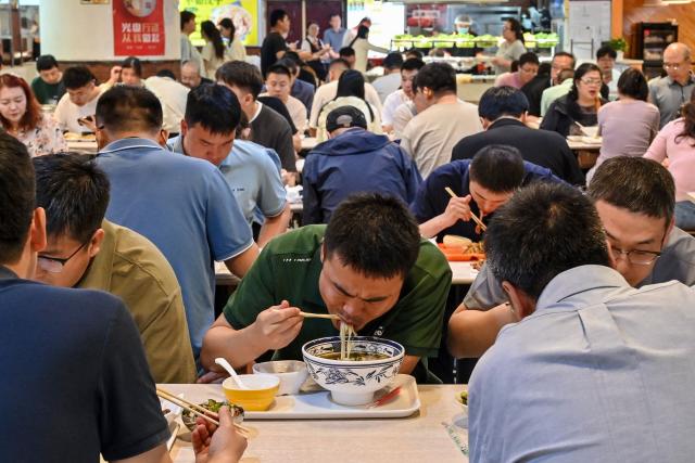 People have lunch at a canteen in Beijing on June 17, 2026. (Photo by ADEK BERRY / AFP)