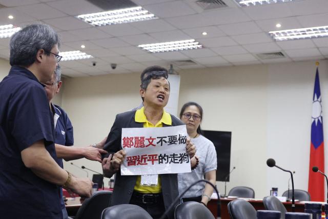 A protester shouts slogans and holds a sign urging KMT Chairwoman Cheng Li-wun to not have close ties with China's President Xi Jinping at the Kuomintang (KMT) headquarters before a news conference in Taipei on June 17, 2026. (Photo by I-HWA CHENG / AFP)