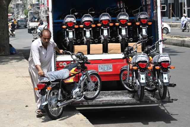 A worker unloads motorcycles from a truck along a street in Karachi on June 17, 2026. (Photo by Rizwan TABASSUM / AFP)