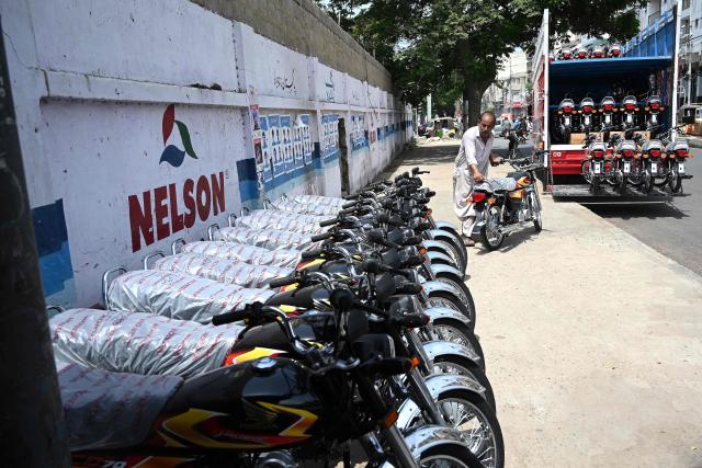 A worker unloads motorcycles from a truck along a street in Karachi on June 17, 2026. (Photo by Rizwan TABASSUM / AFP)