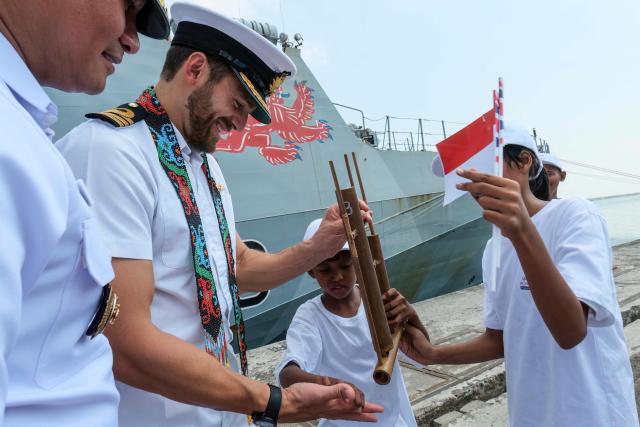 Commanding Officer of the British Royal Navy (HMS) Tamar Thomas S. Lindsey (2nd L) tries out a traditional angklung musical instrument during a visit to Tanjung Priok Port in Jakarta on June 17, 2026. (Photo by BAY ISMOYO / AFP)