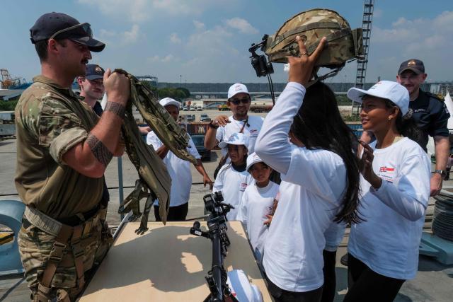 Indonesian primary school children try on military helmets while visiting the British Royal Navy (HMS) Tamar patrol vessel at Tanjung Priok Port in Jakarta on June 17, 2026. (Photo by BAY ISMOYO / AFP)