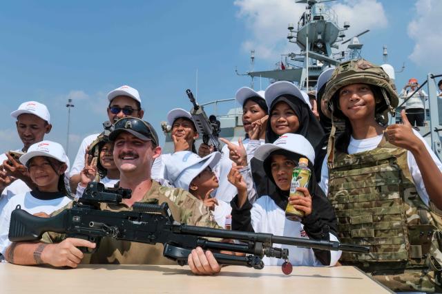 Indonesian primary school children try on military helmets and bulletproof vests while visiting the British Royal Navy (HMS) Tamar patrol vessel at Tanjung Priok Port in Jakarta on June 17, 2026. (Photo by BAY ISMOYO / AFP)