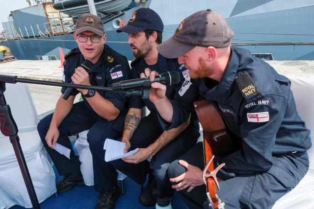 Three crew members of the British Royal Navy (HMS) Tamar patrol vessel sing a song during their visit to Tanjung Priok Port in Jakarta on June 17, 2026. (Photo by BAY ISMOYO / AFP)