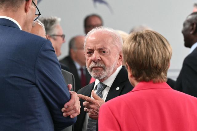 Brazil's President Luiz Inacio Lula da Silva (c) reacts as he speaks with Germany’s Chancellor Friedrich Merz and IMF Managing Director Kristalina Georgieva ahead of a morning work meeting to “revive balanced, inclusive, and sustainable economic growth for the benefit of all” in the presence of the G7 countries, partner countries, the International Monetary Fund, and the OECD, as part of the G7 summit, in Evian, eastern France, on June 17, 2026. G7 leaders will discuss on June 17, 2026, the security risks posed by AI and social media on the last day of a summit dominated by US the President, before host French President  dines with his US counterpart at the Palace of Versailles. The three-day summit of the leaders of Canada, France, Germany, Italy, Japan,B ritain and the United States has focused intensely on the US' deal to end the war with Iran and efforts to pressure Russia into brokering peace with Ukraine. (Photo by Mandel NGAN / AFP)