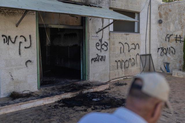 A Palestinian man walks past the damage mosque reportedly burnt by Israeli settlers over night, with one of the Hebrew graffiti reading "nekama" or "revenge" daubed on the wall, in the Israeli occupied West Bank village of Jiljlia, just north of the West bank city of Ramallah on June 17, 2026. Expanding Israeli settlements has been a policy under successive Israeli governments but has accelerated under the current prime minister's coalition, which is backed by far-right allies. More than 500,000 Israelis now live in the West Bank. excluding east Jerusalem, in settlements that are illegal under international law, among some three million Palestinians. (Photo by ilia YEFIMOVICH / AFP) / 