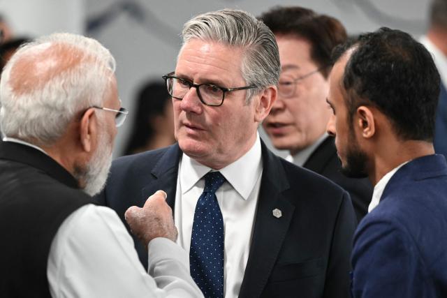 Britain's Prime Minister Keir Starmer (c) reacts as he speaks with India's Prime Minister Narendra Modi (L) ahead of a morning work meeting to “revive balanced, inclusive, and sustainable economic growth for the benefit of all” in the presence of the G7 countries, partner countries, the International Monetary Fund, and the OECD, as part of the G7 summit, in Evian, eastern France, on June 17, 2026. G7 leaders will discuss on June 17, 2026, the security risks posed by AI and social media on the last day of a summit dominated by US the President, before host French President  dines with his US counterpart at the Palace of Versailles. The three-day summit of the leaders of Canada, France, Germany, Italy, Japan,B ritain and the United States has focused intensely on the US' deal to end the war with Iran and efforts to pressure Russia into brokering peace with Ukraine. (Photo by Mandel NGAN / POOL / AFP)