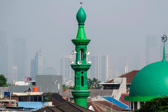 A mosque's minaret (C) is seen as buildings in the background are shrouded in haze in Jakarta on June 17, 2026. (Photo by BAY ISMOYO / AFP)