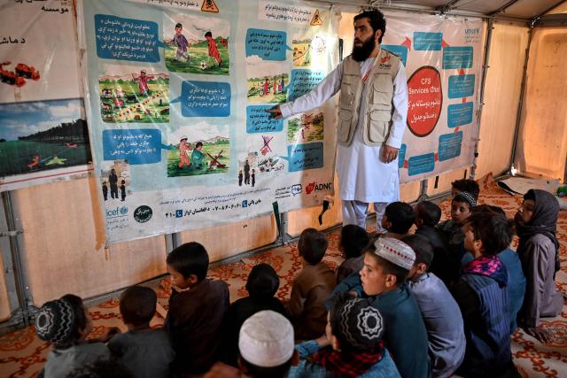 An Afghan volunteer teaches refugee children inside a temporary classroom at Nasaji Pul village in the Daman district of Afghanistan's Kandahar on June 17, 2026. (Photo by Sanaullah SEIAM / AFP)