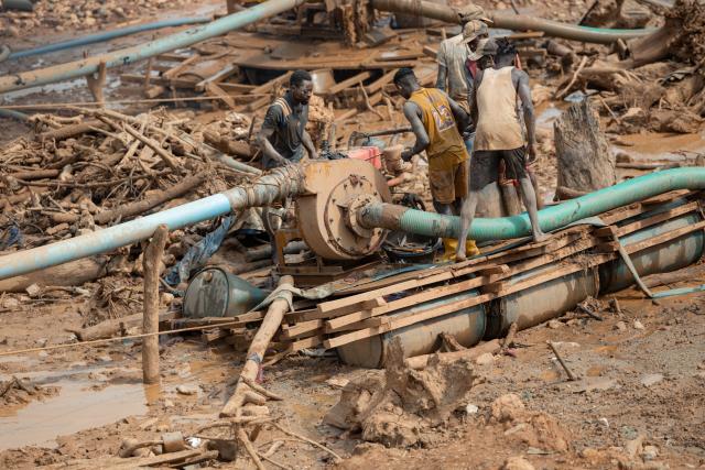Men work inside an artisanal mining pit, operating a suction pipe to transport rock to the surface, where women sort material containing gold particles at a mine in Mongbwalu, Ituri Province, on June 16, 2026. The latest Ebola outbreak in the Democratic Republic of the Congo, declared on May 15, 2026, has mainly affected the remote, conflict-weary northeastern province of Ituri. Health officials warn that population movements linked to artisanal mining, displacement and insecurity are hampering containment efforts in a region where no approved vaccine exists for this Ebola strain. (Photo by Jospin Mwisha / AFP)