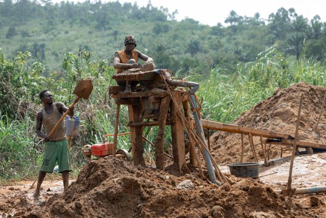 Miners pour gold-bearing sand into a crushing machine equipped with a concentration table lined with carpets and blankets designed to trap fine gold particles at an artisanal mine in Mongbwalu, Ituri province, on June 16, 2026. The latest Ebola outbreak in the Democratic Republic of the Congo, declared on May 15, 2026, has mainly affected the remote, conflict-weary northeastern province of Ituri. Health officials warn that population movements linked to artisanal mining, displacement and insecurity are hampering containment efforts in a region where no approved vaccine exists for this Ebola strain. (Photo by Jospin Mwisha / AFP)