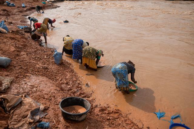 Women artisanal miners wash sand and rocks containing traces of gold in the Iga Barriere River, near the gold-trading hub of Iga Barriere, Ituri Province, on June 16, 2026. The latest Ebola outbreak in the Democratic Republic of the Congo, declared on May 15, 2026, has mainly affected the remote, conflict-weary northeastern province of Ituri. Health officials warn that population movements linked to artisanal mining, displacement and insecurity are hampering containment efforts in a region where no approved vaccine exists for this Ebola strain. (Photo by Jospin Mwisha / AFP)