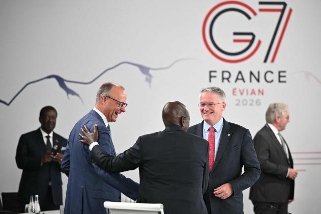 Germany’s Chancellor Friedrich Merz (L) shakes hands with Kenya's President William Ruto next to Secretary-General of the Organisation for Economic Co-operation and Development (OECD) Mathias Cormann ahead of a morning work meeting to “revive balanced, inclusive, and sustainable economic growth for the benefit of all” in the presence of the G7 countries, partner countries, the International Monetary Fund, and the OECD, as part of the G7 summit, in Evian, eastern France, on June 17, 2026. G7 leaders will discuss on June 17, 2026, the security risks posed by AI and social media on the last day of a summit dominated by US the President, before host French President  dines with his US counterpart at the Palace of Versailles. The three-day summit of the leaders of Canada, France, Germany, Italy, Japan, Britain and the United States has focused intensely on the US' deal to end the war with Iran and efforts to pressure Russia into brokering peace with Ukraine. (Photo by Mandel NGAN / POOL / AFP)