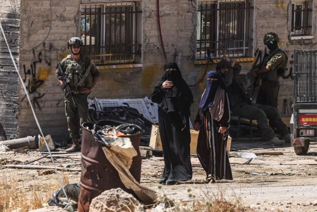 Israeli soldiers stand by as Palestinian women look on as Israeli bulldozers demolish a Palestinian home, which the Israeli authorities say was built without permission, in Ar-Rifaiyya village, south of the Israeli-occupied Palestinian West Bank city of Hebron on June 17, 2026. Israel, whose army has occupied the West Bank since 1967, demolishes the homes of Palestinians which it says have been built without a permit. (Photo by HAZEM BADER / AFP) / 