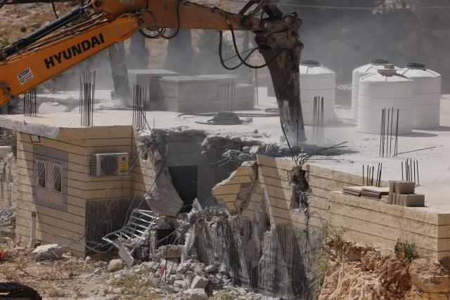 A bulldozer is guarded by Israeli security forces it demolishes a Palestinian home, which the Israeli authorities say were built without permission, in Ar-Rifaiyya village, south of the Israeli-occupied Palestinian West Bank city of Hebron on June 17, 2026. Israel, whose army has occupied the West Bank since 1967, demolishes the homes of Palestinians which it says have been built without a permit. (Photo by HAZEM BADER / AFP) / 