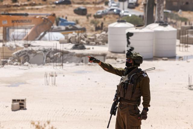 An Israel soldier stands guard on the roof of a Palestinian home being bulldozed because the Israel authorities say it was built without permission, in Ar-Rifaiyya village, south of the Israel-occupied Palestinian West Bank city of Hebron on June 17, 2026. Israel, whose army has occupied the West Bank since 1967, demolishes the homes of Palestinians which it says have been built without a permit. (Photo by HAZEM BADER / AFP) / 
