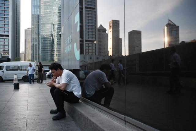A man smokes outside an office building in Beijing on June 17, 2026. (Photo by GREG BAKER / AFP)