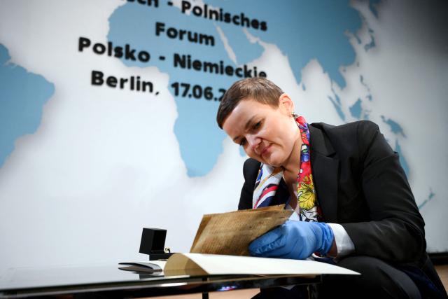 Polish Minister of Culture Marta Cienkowska looks at medieval parchment leaves containing part of the text of the Polish hymn "Gaude Mater Polonia," estimated to date from the late 14th century, as cultural artifacts looted by the German occupying forces during World War II are restituted to Poland, during the German-Polish Forum at the Foreign Ministry in Berlin on June 17, 2026. (Photo by RALF HIRSCHBERGER / AFP)