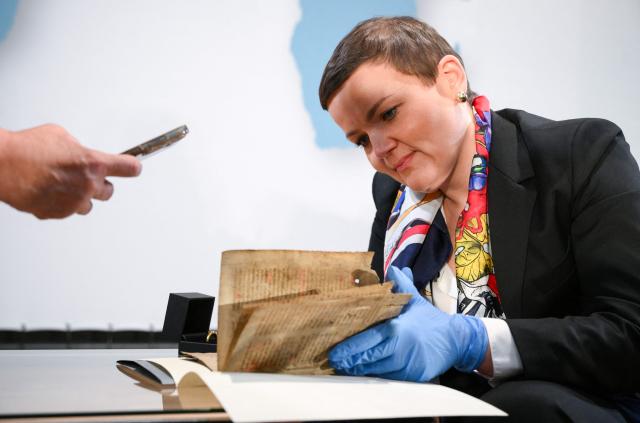 Polish Minister of Culture Marta Cienkowska looks at medieval parchment leaves containing part of the text of the Polish hymn "Gaude Mater Polonia," estimated to date from the late 14th century, as cultural artifacts looted by the German occupying forces during World War II are restituted to Poland, during the German-Polish Forum at the Foreign Ministry in Berlin on June 17, 2026. (Photo by RALF HIRSCHBERGER / AFP)