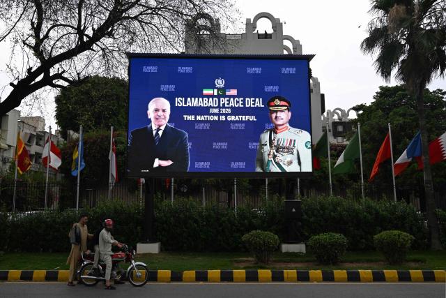 Commuters ride past an electronic board featuring Pakistan's Prime Minister Shehbaz Sharif (L) with Army Chief and Field Marshal Syed Asim Munir, displayed in front of the Serena Hotel in Islamabad on June 17, 2026, after the US–Iran peace deal announcement. Top officials from the United States and Iran will meet at a luxury mountainside resort in Switzerland on June 19, to sign a deal -- which Pakistan has helped mediate -- to bring the Middle East war to an end. (Photo by Aamir QURESHI / AFP)