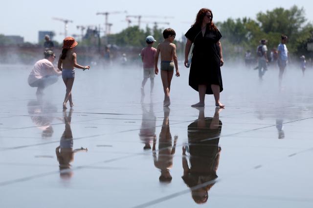 People cool off in a reflecting pool in Bordeaux, south-western France, on June 17, 2026. A heatwave will hit France on June 17, 2026 and last for several days, right in the middle of the baccalaureate exams, with temperatures that could reach up to 40°C in some areas on June 21, the first day of summer. (Photo by ROMAIN PERROCHEAU / AFP)