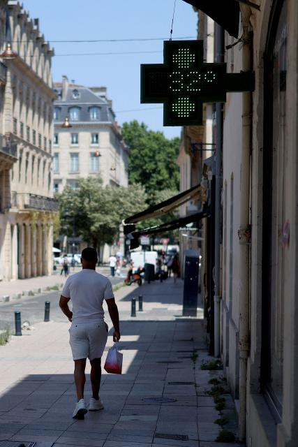 A passerby walks beneath a pharmacy sign displaying the temperature of 32 degrees celsius in Bordeaux, south-western France, on June 17, 2026. A heatwave will hit France on June 17, 2026 and last for several days, right in the middle of the baccalaureate exams, with temperatures that could reach up to 40°C in some areas on June 21, the first day of summer. (Photo by ROMAIN PERROCHEAU / AFP)