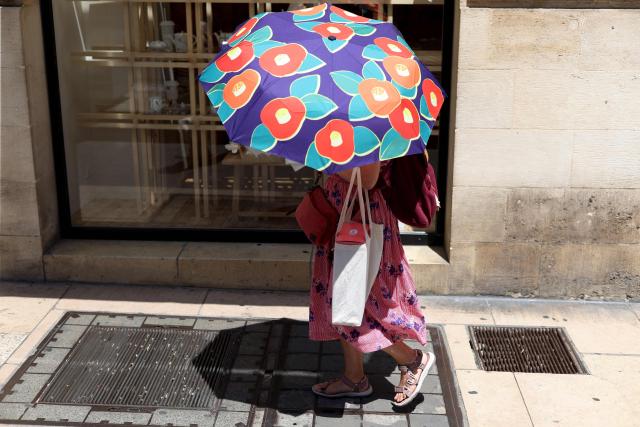 A woman shelters from the sun with an umbrella in Bordeaux, south-western France, on June 17, 2026. A heatwave will hit France on June 17, 2026 and last for several days, right in the middle of the baccalaureate exams, with temperatures that could reach up to 40°C in some areas on June 21, the first day of summer. (Photo by ROMAIN PERROCHEAU / AFP)