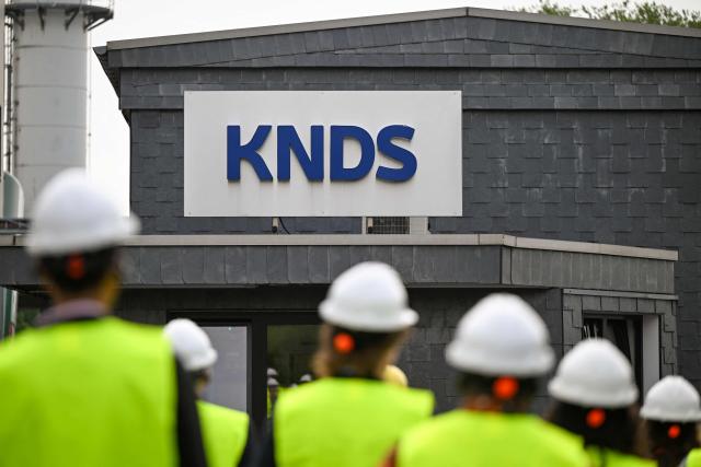 Visitors walk in front of a sign of KNDS Deutschland Tracks GmbH during a visit as part of the Cleantech Future Festival in Remscheid, western germany on June 17, 2026. KNDS Deutschland Tracks GmbH is a global leader in the development and manufacture of tracks and undercarriage components for tanks and armoured vehicles. The international Future Cleantech Festival brings together high-level UN climate policy and research with practical insights into European heavy industry (Photo by Ina FASSBENDER / AFP)