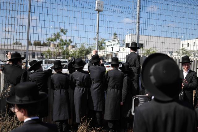 Ultra-Orthodox Jews look through a fence outside Bet Lid military prison during a protest against military conscription in Kfar Yona on June 17, 2026. Israeli lawmakers voted on June 10 to advance a bill that would allow most ultra-Orthodox Jewish men to avoid military conscription, despite fierce opposition protests. Ultra-orthodox men have largely been exempted from service throughout Israel's modern history, but the Supreme Court has repeatedly challenged that status in recent years culminating in a 2024 ruling that the government must conscript them. (Photo by Ilia YEFIMOVICH / AFP)
