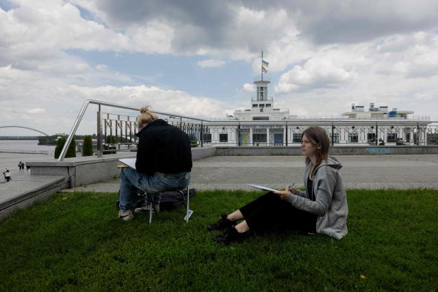 Teenagers are seen drawing in the Podil neighbourhood in Kyiv on June 17, 2026, amid the Russian invasion of Ukraine. (Photo by Tetiana DZHAFAROVA / AFP)