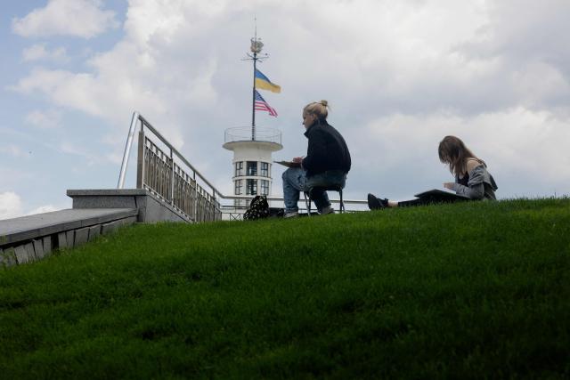 Teenagers are seen drawing in the Podil neighbourhood in Kyiv on June 17, 2026, amid the Russian invasion of Ukraine. (Photo by Tetiana DZHAFAROVA / AFP)
