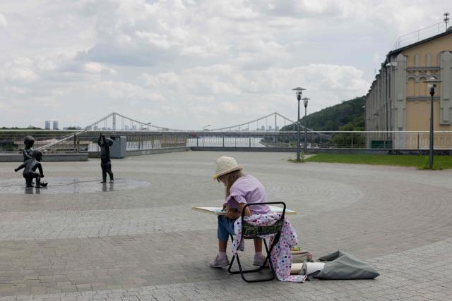 A little girl is seen drawing in the Podil neighbourhood in Kyiv on June 17, 2026, amid the Russian invasion of Ukraine. (Photo by Tetiana DZHAFAROVA / AFP)