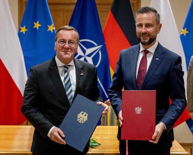Poland's Deputy Prime Minister and Defence Minister Wladyslaw Kosiniak-Kamysz (R) and Germany's Defence Minister Boris Pistorius pose as they exchange documents after signing a defence agreement between Poland and Germany at the Defence Ministry in Warsaw, Poland, on June 17, 2026. After signing defence pacts with France and UK, Warsaw signed an agreement with Germany on June 17 -- but its sweep was trimmed fearing right-wing opposition and the prospect of a presidential veto. Poland -- the only NATO member to border both Russia and Ukraine -- has sought to bolster its defence in more than four years of Moscow's invasion next door. The agreements were signed on the 35th anniversary of the 1991 Treaty of Good Neighbourship, which set up security, economic, and cultural cooperation between the two countries. (Photo by Wojtek RADWANSKI / AFP)