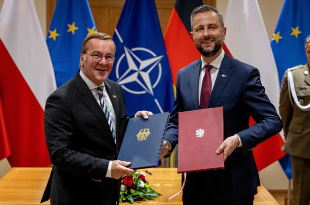 Poland's Deputy Prime Minister and Defence Minister Wladyslaw Kosiniak-Kamysz (R) and Germany's Defence Minister Boris Pistorius pose as they exchange documents after signing a defence agreement between Poland and Germany at the Defence Ministry in Warsaw, Poland, on June 17, 2026. After signing defence pacts with France and UK, Warsaw signed an agreement with Germany on June 17 -- but its sweep was trimmed fearing right-wing opposition and the prospect of a presidential veto. Poland -- the only NATO member to border both Russia and Ukraine -- has sought to bolster its defence in more than four years of Moscow's invasion next door. The agreements were signed on the 35th anniversary of the 1991 Treaty of Good Neighbourship, which set up security, economic, and cultural cooperation between the two countries. (Photo by Wojtek RADWANSKI / AFP)