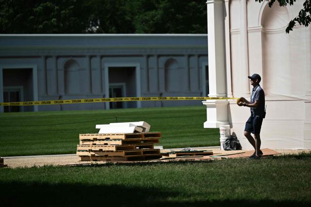 A worker sets up a yellow tape as preparations continue for the "Great American State Fair" on the National Mall in Washington, DC, JJune 17, 2026. The "Great American State Fair" will be held from June 25 to July 10, 2026, to celebrate the 250th anniversary of US independence. (Photo by Brendan SMIALOWSKI / AFP)