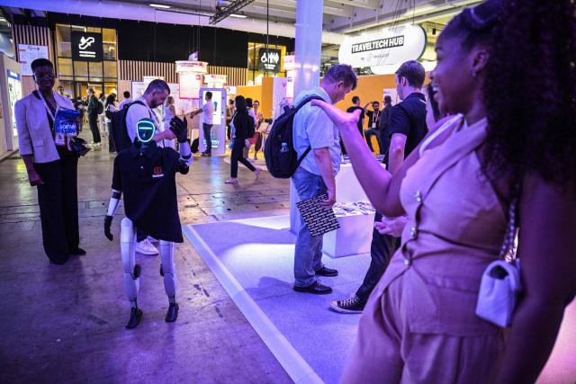 An attendee blows a kiss to a Korben company robot at the VivaTech technology startups and innovation fair at the Paris Expo Porte de Versailles, in Paris on June 17, 2026. (Photo by JULIEN DE ROSA / AFP)