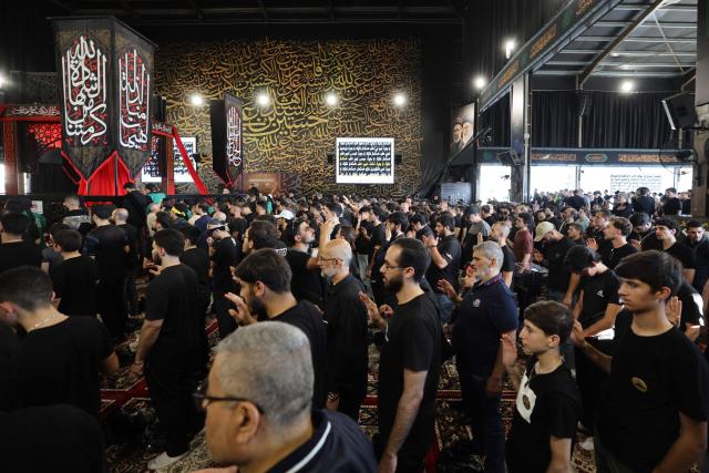 People react as Hezbollah Secretary-General Sheikh Naim Qassem (not pictured) addresses crowds via a giant screen during the first day of Ashura commemorations at the mausoleum of former Hezbollah leader Hassan Nasrallah in Beirut’s southern suburbs on June 17, 2026. Qassem said on June 17 that Lebanon's negotiations with Israel should be limited to "mutual security", and that the country's main demand should be restoring its sovereignty after Israeli troops invaded the south. (Photo by Anwar AMRO / AFP)