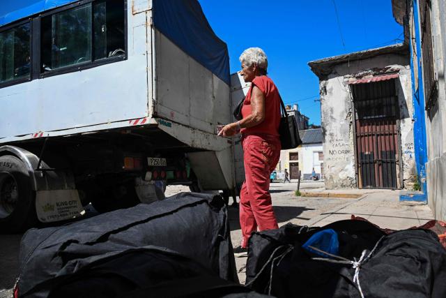 A woman stands next to luggage as she waits for interprovincial transport in Havana on June 16, 2026. New restrictions on interprovincial transport in Cuba come into force on June 18, 2026, with trains running every 16 days, few weekly coaches and a state system for allocating tickets according to criteria of "urgency", amid a severe fuel shortage, under pressure from Washington. (Photo by YAMIL LAGE / AFP)