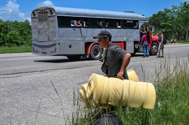 People board a private lorry transporting passengers to the eastern provinces on the National Motorway on the outskirts of Havana on June 16, 2026. New restrictions on interprovincial transport in Cuba come into force on June 18, 2026, with trains running every 16 days, few weekly coaches and a state system for allocating tickets according to criteria of "urgency", amid a severe fuel shortage, under pressure from Washington. (Photo by YAMIL LAGE / AFP)