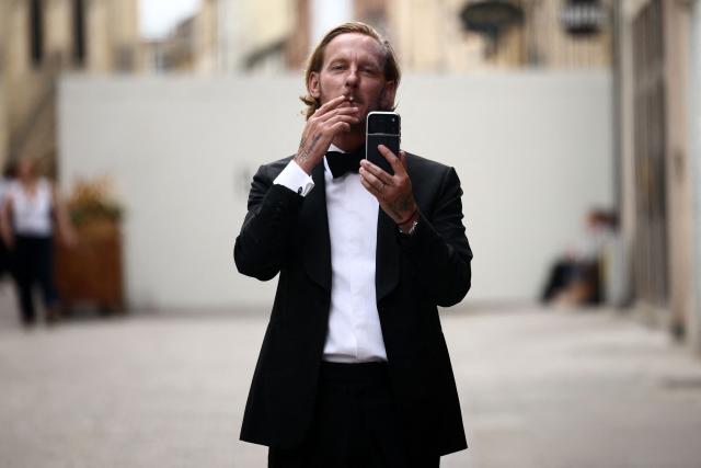 British actor-turned-politician/activist Laurence Fox gestures with his phone, live-streaming, as he stands behind  security barriers after arriving to attend a speech by British far-right activist Tommy Robinson, real name Stephen Yaxley-Lennon, to The Oxford Union, in Oxford, western England, on June 17, 2026. (Photo by Henry NICHOLLS / AFP)